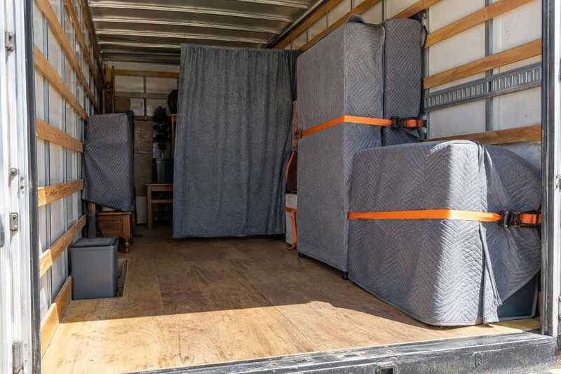 Mobilier sanglé derrière une cloison de couvertures dans la caisse d'un camion