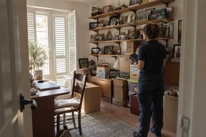 Déménageuse faisant l'inventaire d'une pièce remplie de souvenirs accumulés