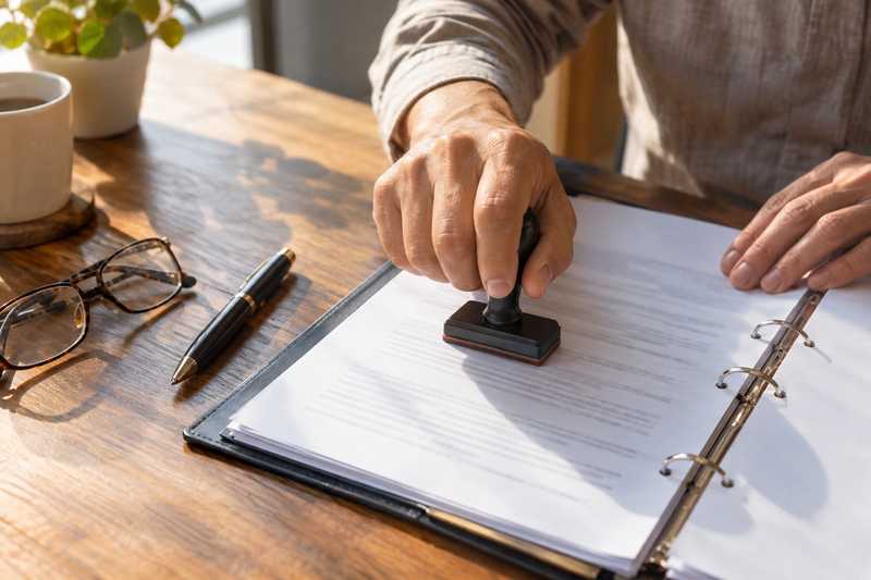Main apposant un tampon sur une page d'inventaire dans un classeur ouvert