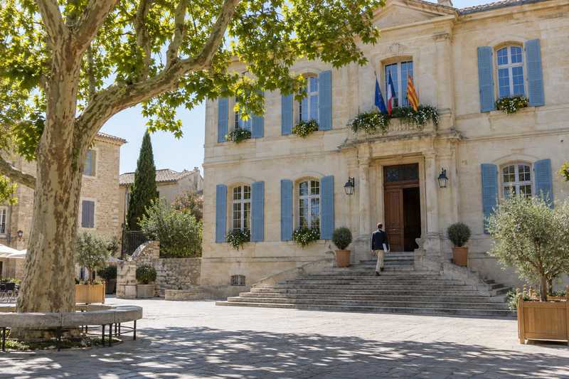 Personne montant les marches d'une mairie provençale avec une pochette